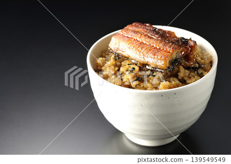 A mini eel rice bowl photographed alone against a black background. A mini eel rice bowl photographed alone against a black background. 139549549