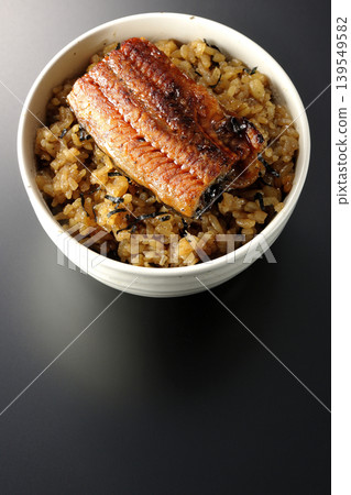 A mini eel rice bowl photographed alone against a black background. A mini eel rice bowl photographed alone against a black background. 139549582