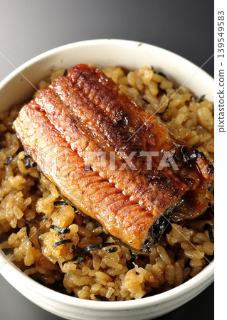 A mini eel rice bowl photographed alone against a black background. A mini eel rice bowl photographed alone against a black background. 139549583