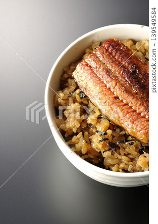 A mini eel rice bowl photographed alone against a black background. A mini eel rice bowl photographed alone against a black background. 139549584