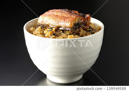 A mini eel rice bowl photographed alone against a black background. A mini eel rice bowl photographed alone against a black background. 139549589