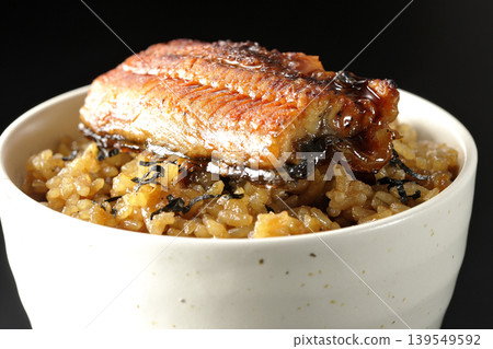 A mini eel rice bowl photographed alone against a black background. A mini eel rice bowl photographed alone against a black background. 139549592