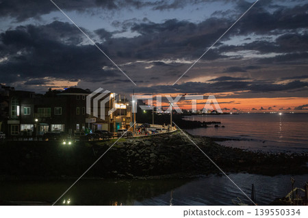 [South Korea] Sunset over a cloudy sky and houses viewed from the coast of Jeju Island 139550334