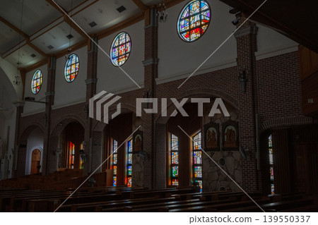 [South Korea] Dimly lit chapel and colorful stained glass windows of a Catholic church on Jeju Island 139550337