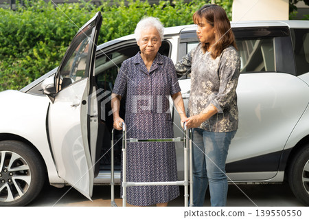 Caregiver help Asian elderly woman disability patient get in her car. Caregiver help Asian elderly woman disability patient get in her car. 139550550