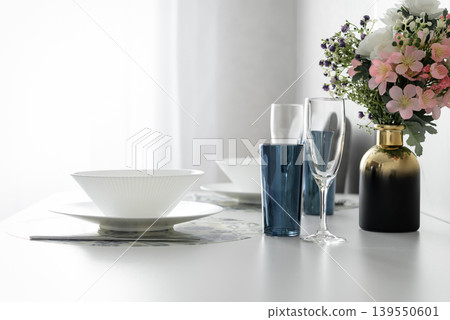 Modern dining table setting with flowers in bright apartment interior Modern dining table setting with flowers in bright apartment interior 139550601