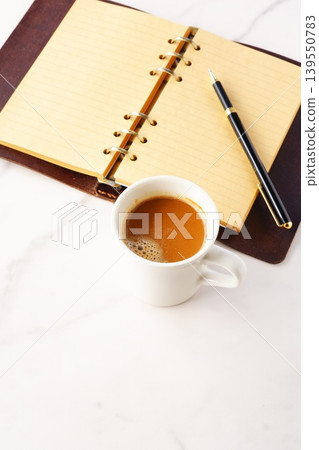 Image of a man working at his desk with a system organizer while drinking a cafe latte, a coffee with plenty of milk Image of a man working at his desk with a system organizer while drinking a cafe latte, a coffee with plenty of milk 139550783