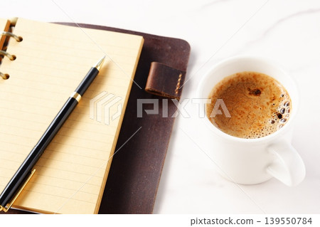 Image of a man working at his desk with a system organizer while drinking a cafe latte, a coffee with plenty of milk Image of a man working at his desk with a system organizer while drinking a cafe latte, a coffee with plenty of milk 139550784