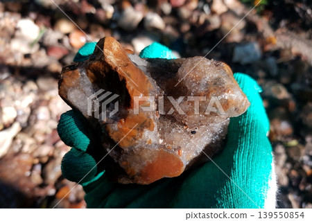 Gloved hand clasping a gnarly mineral chunk, displaying earthy hues and sparkling crystal formations. A neat raw find from nature's bounty Gloved hand clasping a gnarly mineral chunk, displaying earthy hues and sparkling crystal formations. A neat raw find from nature's bounty 139550854