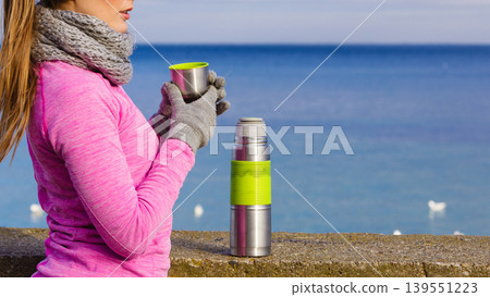 Fit woman in cold day warming up drink tea Fit woman in cold day warming up drink tea 139551223