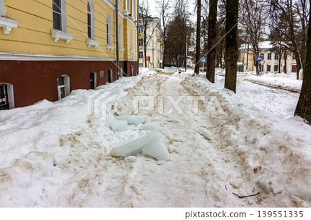 Massive ice chunks litter a snowy urban path near a building, highlighting winter hazards and the urgent need for safety and clearance Massive ice chunks litter a snowy urban path near a building, highlighting winter hazards and the urgent need for safety and clearance 139551335