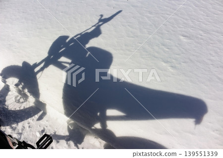 Long shadow of an electric fatbike stretches across pristine snow, capturing winter adventure and sunny ride vibes 139551339