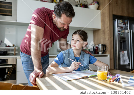 Father homeschooling daughter at home while teaching and supporting her learning. Father homeschooling daughter at home while teaching and supporting her learning. 139551402