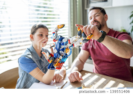 Father teaching daughter robotics at home while homeschooling with educational toy. 139551406
