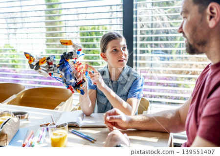 Father teaching daughter robotics at home while homeschooling with educational toy. 139551407