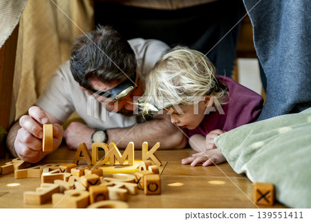 Dad and child building and playing in cozy blanket fort. Dad and child building and playing in cozy blanket fort. 139551411