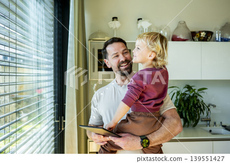 Father showing smart home control to toddler while managing exterior shading system. Father showing smart home control to toddler while managing exterior shading system. 139551427