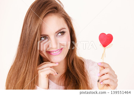 Flirty woman holding red wooden heart on stick 139551464