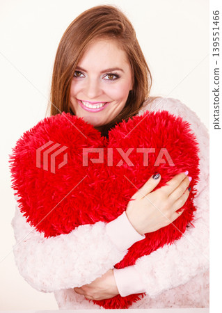 Happy woman holding heart shaped pillow 139551466