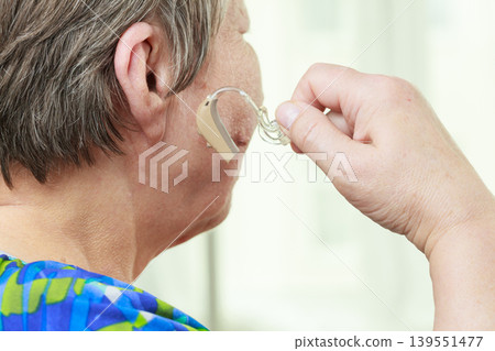 Closeup senior woman using hearing aid Closeup senior woman using hearing aid 139551477