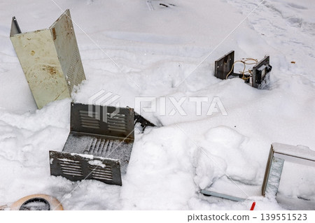 Discarded electronic casings and rusty parts litter fresh snow, evidence of crude dismantling and industrial waste. Winter's chill covers this tech graveyard Discarded electronic casings and rusty parts litter fresh snow, evidence of crude dismantling and industrial waste. Winter's chill covers this tech graveyard 139551523