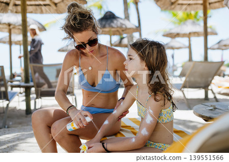 Mother applying sunscreen on daughters skin. Mother applying sunscreen on daughters skin. 139551566