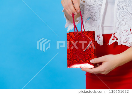 Woman holds red gift bag in hand Woman holds red gift bag in hand 139551622