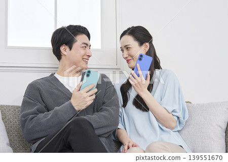A couple talking on their smartphones in the living room A couple talking on their smartphones in the living room 139551670