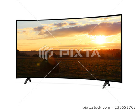 Curved screen tv from angled view with rural landscape with straw roll and sunset sky on screen Curved screen tv from angled view with rural landscape with straw roll and sunset sky on screen 139551703