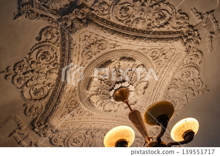 Ornate Soviet stucco ceiling medallion with elaborate foliage and wheat motifs, typical of Stalinist Empire architecture from the 1950s Ornate Soviet stucco ceiling medallion with elaborate foliage and wheat motifs, typical of Stalinist Empire architecture from the 1950s 139551717