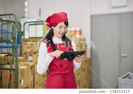 A young woman manages inventory using a tablet in the back room. 139552417