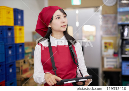 A young woman manages inventory using a tablet in the back room. 139552418