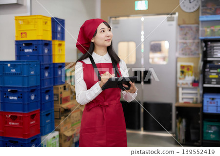 A young woman manages inventory using a tablet in the back room. 139552419