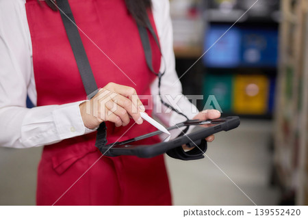 A young woman manages inventory using a tablet in the back room. 139552420