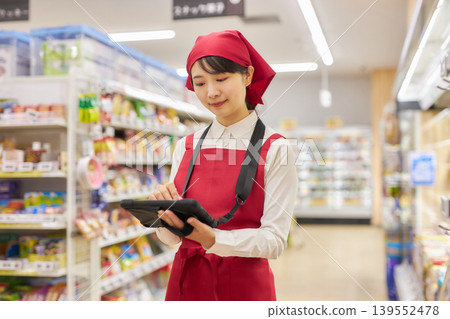 A young woman manages products using a tablet. 139552478