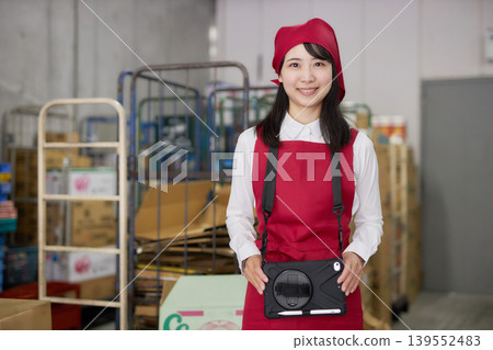 一位年輕女子在後屋使用平板電腦管理庫存。 139552483