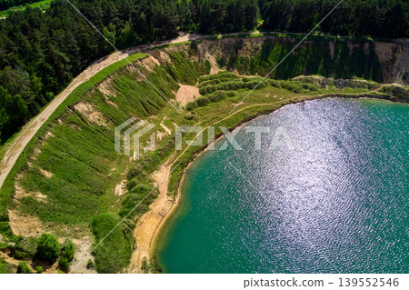 Aerial view of a slope of a sand quarry with a pond, a coastline on a lake Aerial view of a slope of a sand quarry with a pond, a coastline on a lake 139552546