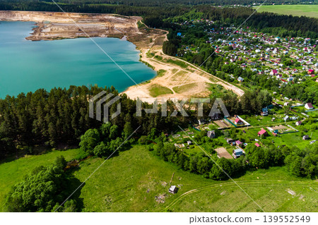 Aerial view of a settlement next to a lake formed on the site of a sand quarry, beautiful countryside landscape Aerial view of a settlement next to a lake formed on the site of a sand quarry, beautiful countryside landscape 139552549