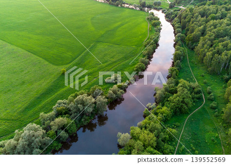 View from a drone of a river flowing among lush green fields View from a drone of a river flowing among lush green fields 139552569