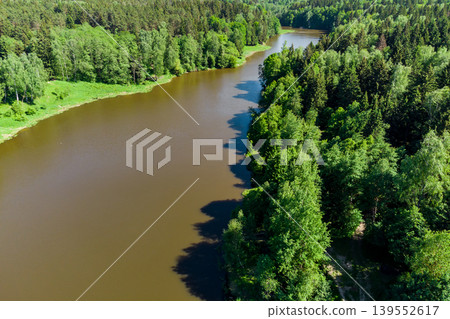An aerial view through the trees of a body of water in a picturesque wilderness area. Pond on the Stradalovka River, Balabanovo, Russia An aerial view through the trees of a body of water in a picturesque wilderness area. Pond on the Stradalovka River, Balabanovo, Russia 139552617