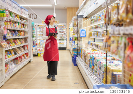 A young woman manages products using a tablet. 139553146