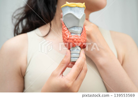 Hyperthyroidism, Overactive Thyroid, Thyroid Lymphoma, Asian woman with thyroid gland human anatomy model. Hyperthyroidism, Overactive Thyroid, Thyroid Lymphoma, Asian woman with thyroid gland human anatomy model. 139553569