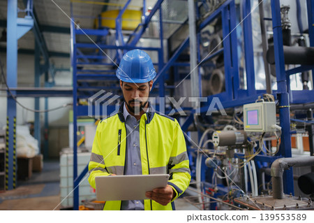 Industrial worker supervising machinery operations in modern production plant. 139553589
