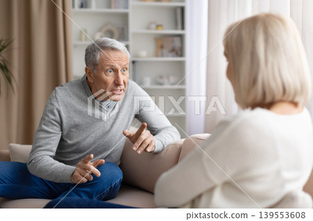 Senior couple arguing at home during emotional discussion, expressing frustration Senior couple arguing at home during emotional discussion, expressing frustration 139553608