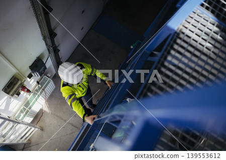 Top view of worker in industrial factory climbing up the ladder. Top view of worker in industrial factory climbing up the ladder. 139553612