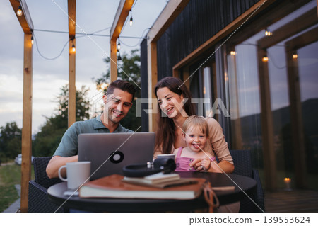 Modern family spending time together on patio, father using laptop. Modern family spending time together on patio, father using laptop. 139553624