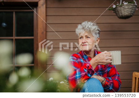 Senior woman with coffee sitting on terrace, resting after gardening. 139553720