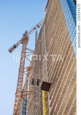 High-rise building under construction with tower crane, urban development and real estate concept High-rise building under construction with tower crane, urban development and real estate concept 139554175