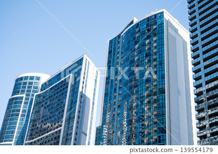 Modern high-rise residential buildings with glass facades against a clear blue sky. 139554179