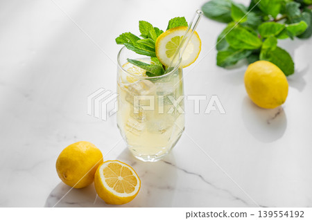 Refreshing lemon mint drink with ice in glass, homemade summer lemonade on marble background Refreshing lemon mint drink with ice in glass, homemade summer lemonade on marble background 139554192